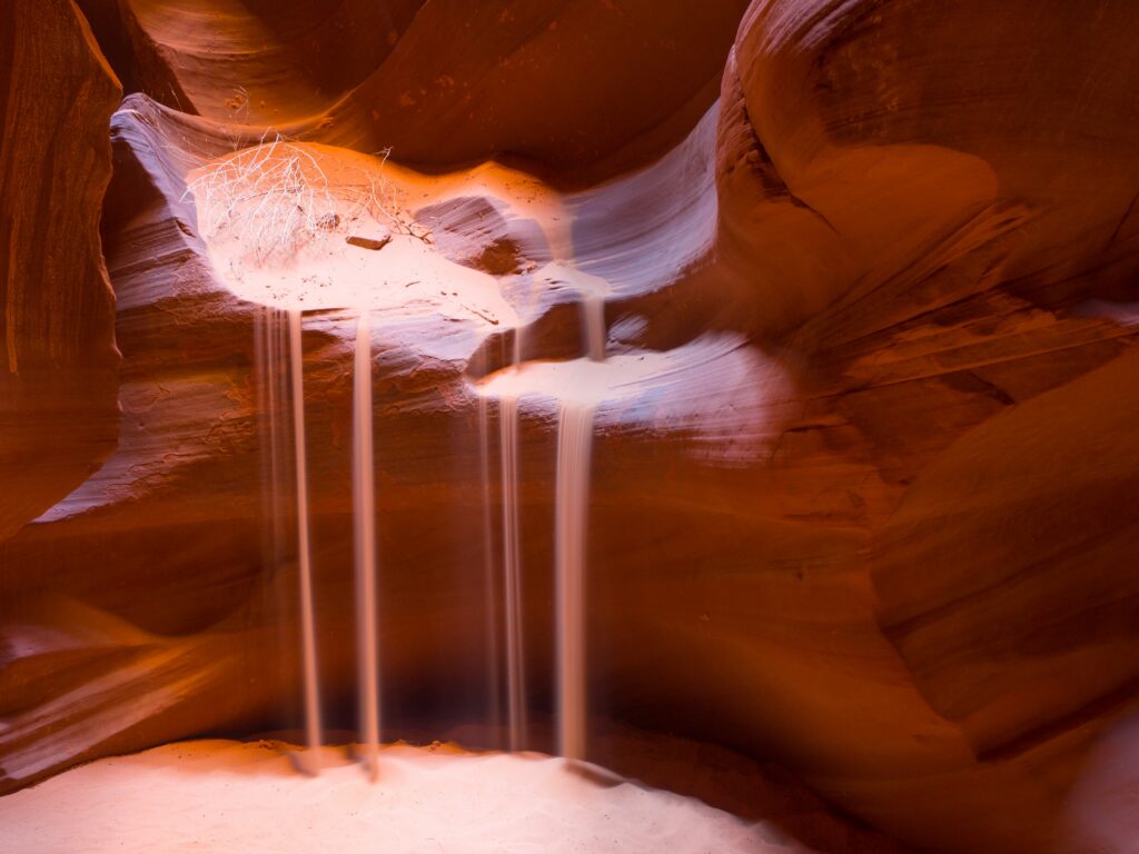 sand pouring over sandstone rocks like a waterfall